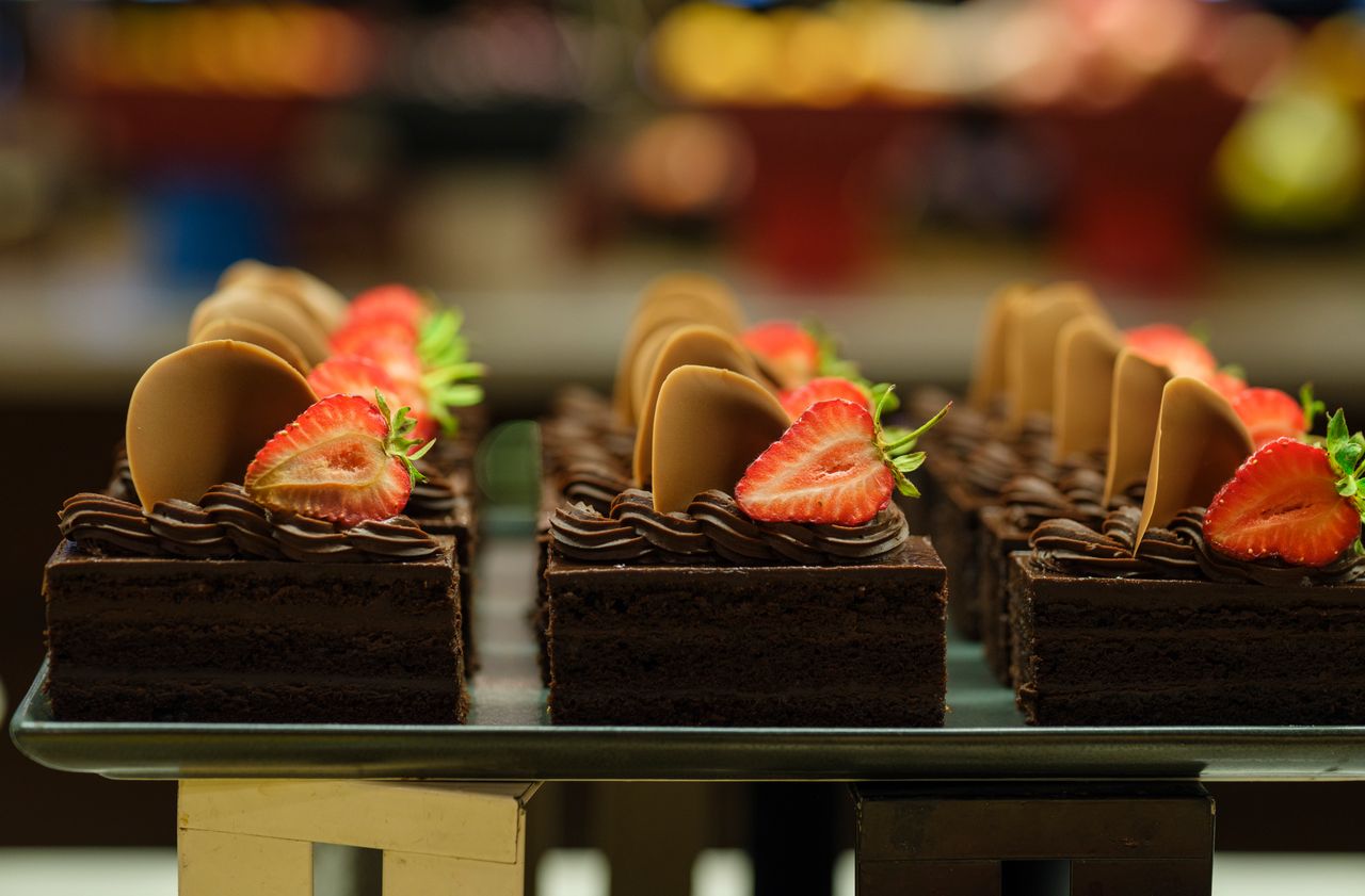 Mouth-watering chocolate cake slices adorned with fresh strawberries and chocolate rounds, perfect for dessert lovers.