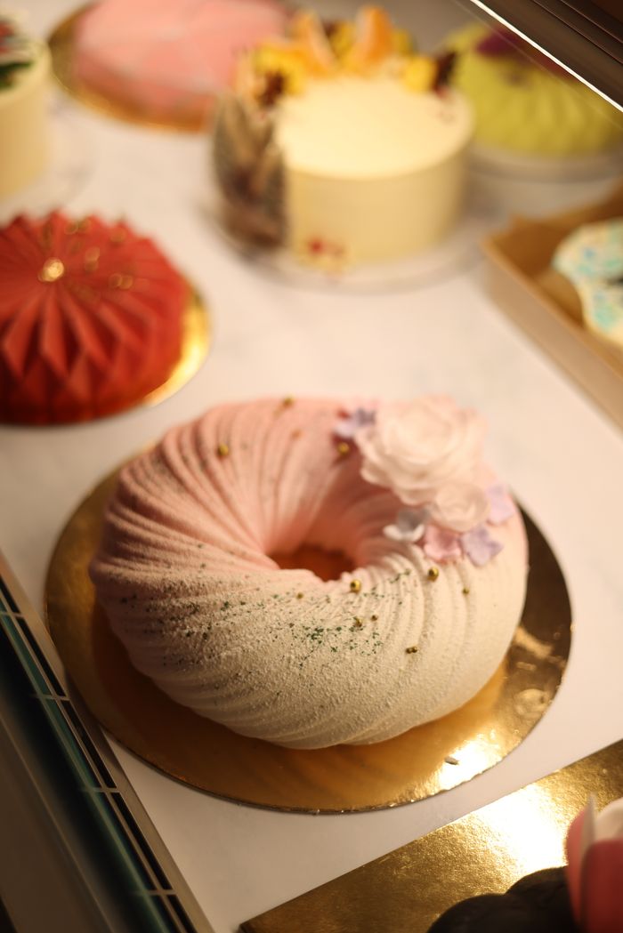 Close-up of elegant dessert cakes in a bakery display with artistic decoration.