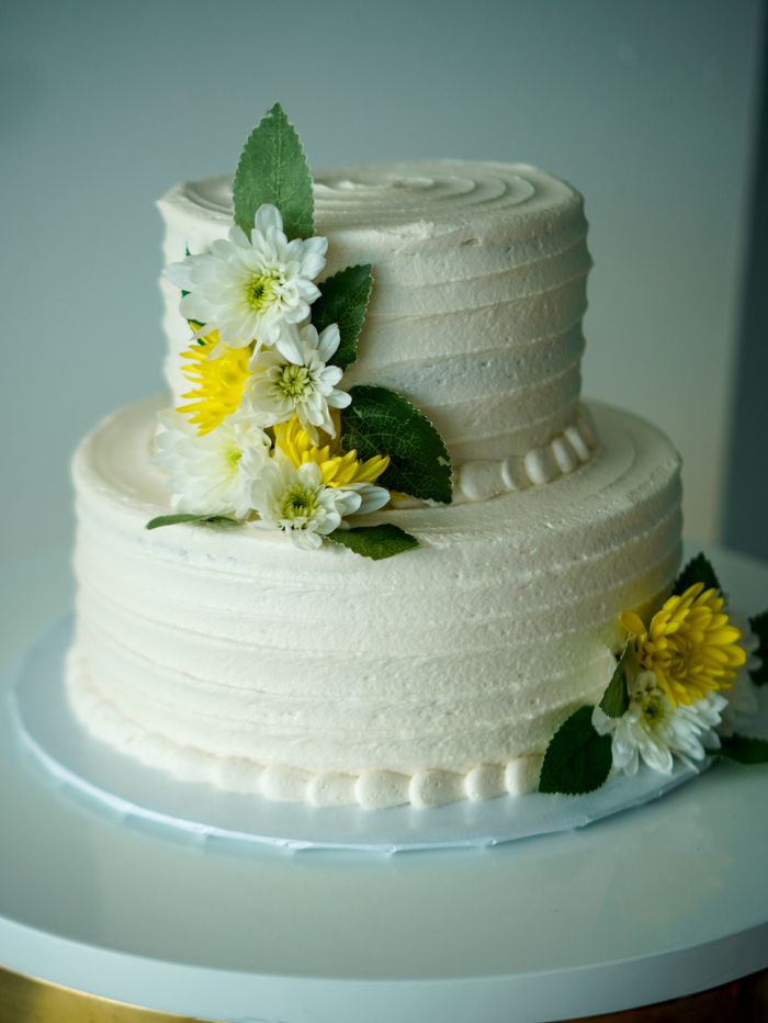services-01 Beautiful minimalist wedding cake adorned with white and yellow flowers for a timeless celebration.